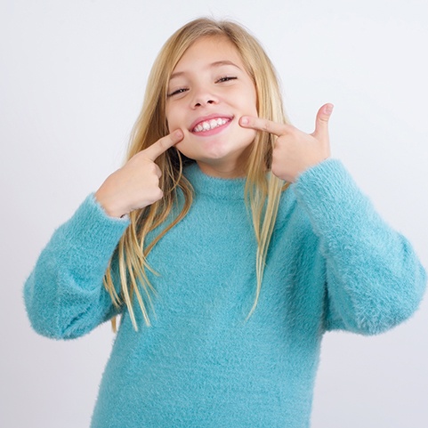 Smiling girl pointing at her teeth