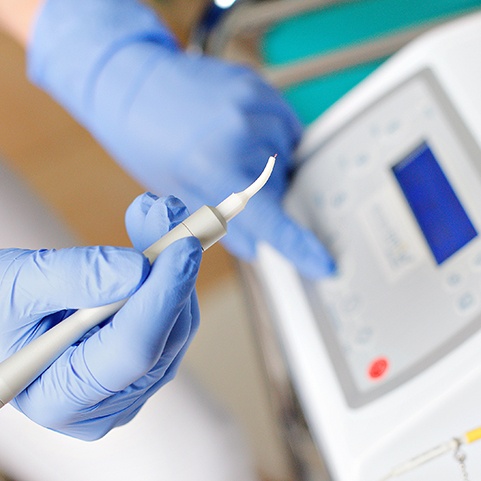 Gloved hands preparing to use soft tissue laser for frenectomy