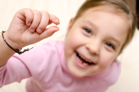 young girl holding loose tooth 